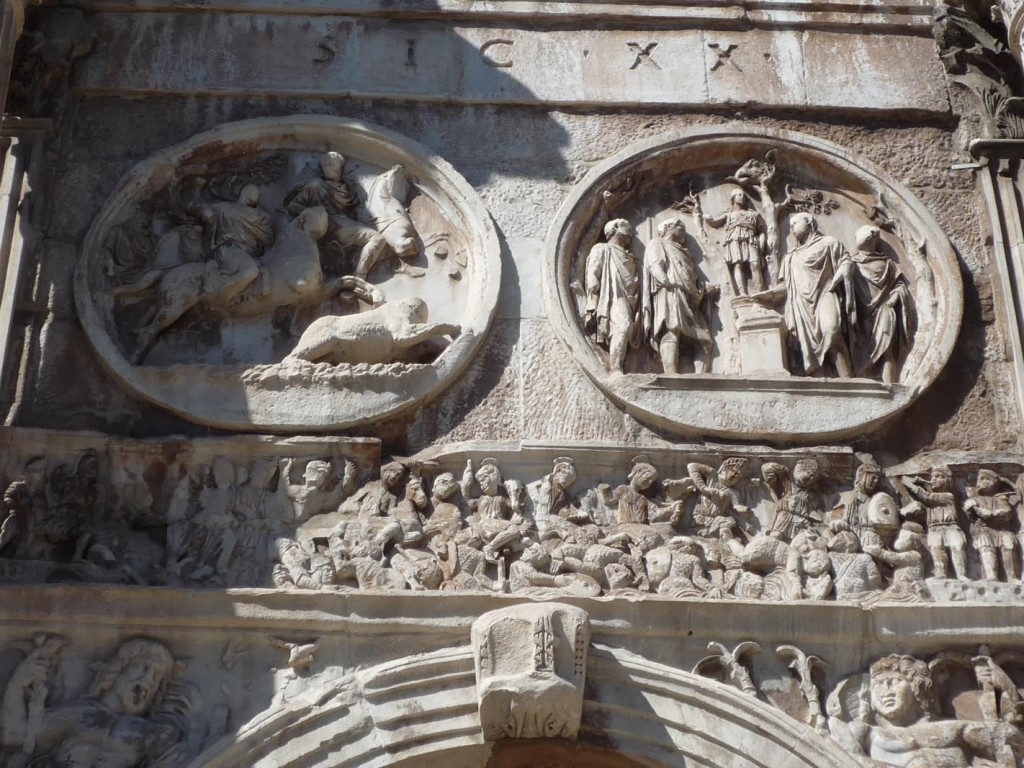 Façade Sud avec les médaillons de l'époque d'Hadrien (Chasse à l'ours et scène de sacrifice à Diane) au dessus du relief représentant la bataille du Pont Milvius. On y voit à gauche le pont avec une personnification du Tibre, au centre la cavalerie de Constantin battant les cataphractaires de Maxence qui se noient et à droite les trompettes appelant les troupes victorieuses.