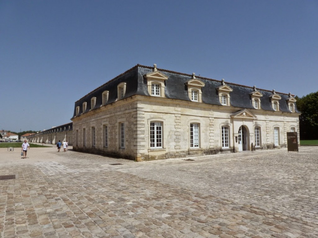  Un pavillon occupe chaque extrémité du long bâtiment, dont l'axe est marqué par une baie ornée d'un fronton triangulaire.