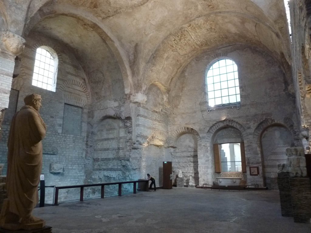 La voute du frigidarium culmine à 14,50m. La piscine occupe l'exèdre du mur nord (à droite) et est encadrée par deux portes bouchées, qui donnaient sur les deux gymnases. 